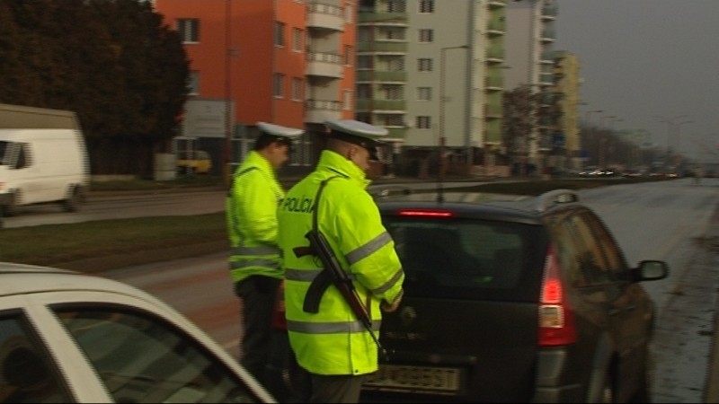 Policajti vyberajú pokuty, auto v pozadí
